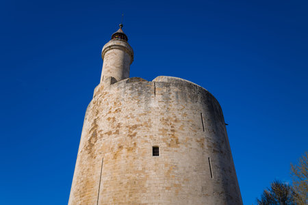 Unknown location - April 2, 2023: The upper section of the Tour de Constance, a large circular medieval stone tower with a lantern, is seen from below against a clear blue sky.のeditorial素材
