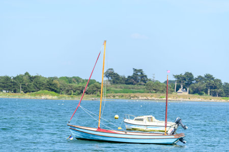 Etel, France - May 31, 2023: Two small boats, including a blue and white sailboat and a white...