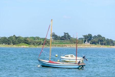 Etel, France - May 31, 2023: Two small boats, including a blue and white sailboat and a white...