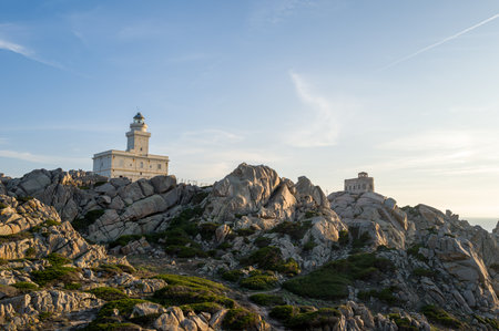 Capo Testa, Italy - September 28, 2023: A lighthouse stands on a rocky hill surrounded by large granite boulders and sparse vegetation at Capo Testa under a clear sky.のeditorial素材