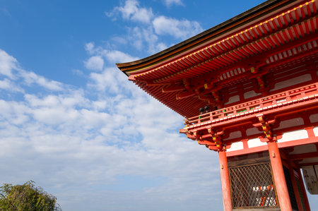 Kyoto, Japan - October 16, 2023: The upper section and roof eaves of the red Niomon Gate at Kiyomizu-dera temple are seen against a blue sky with scattered clouds.のeditorial素材
