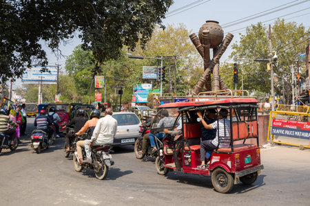 Mathura, India - March 13, 2024: Motorcycles, an e-rickshaw, and cars are seen at a busy...