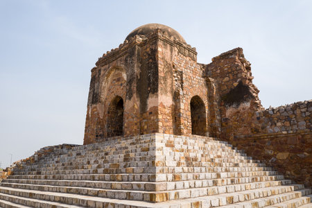 Delhi, India - March 29, 2024: The image shows the remains of a stone mosque with a dome and arched entrances, situated atop a wide flight of stone steps at Feroz Shah Kotla Fort under a clear sky.のeditorial素材