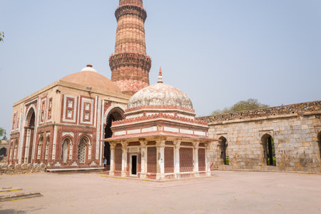 Delhi, India - March 30, 2024: The image shows Imam Zamins Tomb with its white marble dome in the foreground, the Alai Darwaza gate to the left, and the Qutub Minar tower rising in the background at the Qutub Minar complex.のeditorial素材