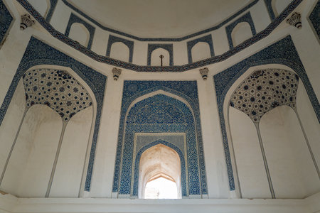 Delhi, India - March 30, 2024: The image shows the interior ceiling and upper walls of Quli Khans Tomb at the Mehrauli Archaeological Complex, featuring arched niches and intricate blue tilework patterns.のeditorial素材