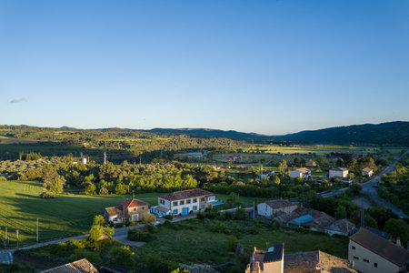 Murillo de Gallego, Spain - May 7, 2024: Elevated view of Murillo de Gallego village with residential houses, green fields, and distant hills under a clear blue sky.のeditorial素材