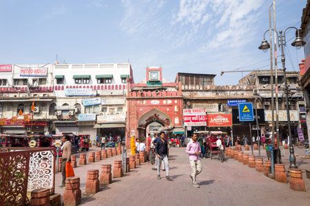 Delhi, India - March 29, 2024: Pedestrians and cycle rickshaws move along a busy street in front of the eastern entrance gate of Fatehpuri Masjid, with commercial buildings, shop signage, and street vendors visible.のeditorial素材
