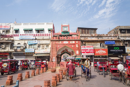 Delhi, India - March 29, 2024: The eastern entrance gate of Fatehpuri Masjid is seen with numerous cycle rickshaws, pedestrians, and surrounding commercial buildings displaying various shop signs and advertisements.のeditorial素材