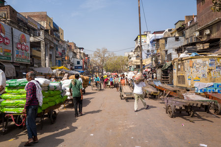Delhi, India - March 29, 2024: The image shows laborers transporting large sacks on handcarts and on...