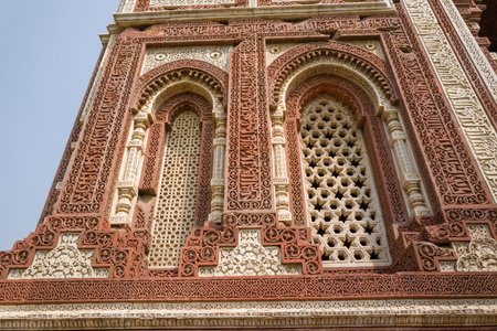 Delhi, India - March 30, 2024: The image shows a close-up of the intricate red sandstone and white marble lattice windows with geometric and floral carvings on the Alai Darwaza gate at the Qutub Minar complex.のeditorial素材