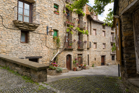 Unknown location - May 6, 2024: View of a narrow cobblestone street bordered by old stone...