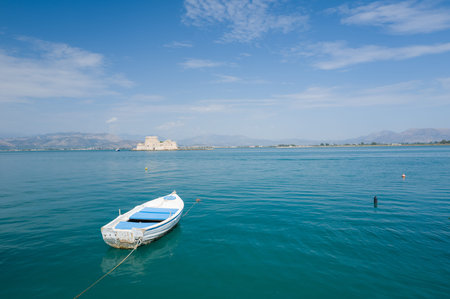 Nauplie, Greece - September 4, 2024: A small white and blue boat is moored on calm water in the...