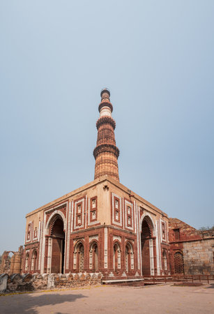 Delhi, India - March 30, 2024: The image shows the Qutub Minar tower rising behind the Alai Darwaza gate, with its red sandstone and white marble inlay, arched entrances, and geometric lattice windows at the Qutub Minar complex.のeditorial素材