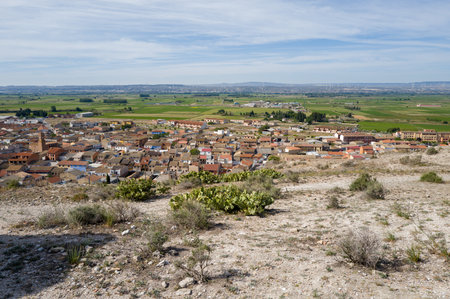 Alfajarin, Spain - May 10, 2024: An elevated view shows the town of Alfajarin with its clustered rooftops in the foreground and expansive agricultural fields stretching into the distance under a partly cloudy sky.のeditorial素材