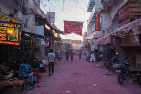 Pushkar, India - March 18, 2022: People are seated at a table outside a restaurant and others walk...