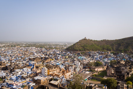Bundi, India - March 20, 2022: The image shows an elevated view over Bundi with densely packed buildings, historic structures, and a green hill with a small pavilion on top under a clear sky.のeditorial素材