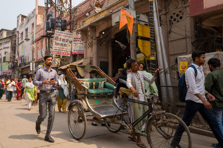 Varanasi, India - March 18, 2024: A rickshaw puller stands beside his cycle rickshaw while...