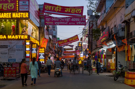 Lucknow, India - March 16, 2024: The image shows a bustling urban street at dusk with illuminated...