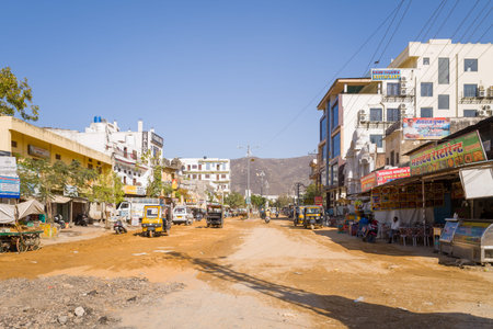 Pushkar, India - March 17, 2022: A wide dirt street is lined with multi-story buildings,...