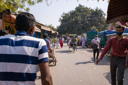 Delhi, India - March 13, 2022: View from behind a rickshaw driver in a blue and white striped shirt...