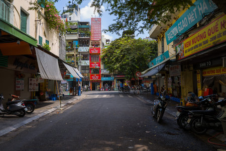 Hanoi, Vietnam - August 29, 2022: The image shows a street lined with parked motorbikes, various...