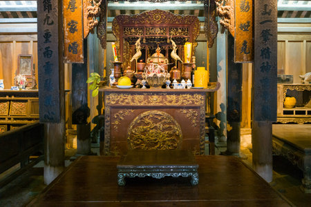 Hanoi, Vietnam - September 15, 2022: A traditional Vietnamese ancestral altar with intricate wood carvings, ritual vessels, ceramic vases, and decorative objects is displayed inside a wooden house at the Museum of Ethnology.のeditorial素材