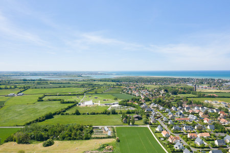 Batteries de Merville, France - June 1, 2021: The image shows an aerial view of the Batteries de Merville, including preserved World War II bunkers, green fields, a modern museum building, and the nearby residential area with the coastline visible in the のeditorial素材