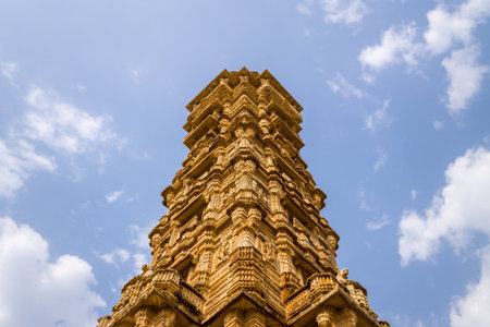 Chittorgarh, India - March 21, 2022: The image shows the upper section of the Vijay Stambh, also known as the Tower of Victory, featuring intricate stone carvings and architectural details against a partly cloudy sky.のeditorial素材