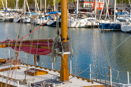 La Rochelle, France - September 1, 2020: Close-up view of a wooden sailboat mast with rigging and ropes, with additional moored sailboats and waterfront buildings visible in the background.のeditorial素材