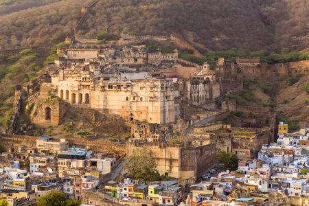 Bundi, India - March 20, 2022: The image shows Garh Palace situated on a hillside above the densely built city of Bundi, with extensive fort walls and surrounding dry hills visible under daylight.のeditorial素材