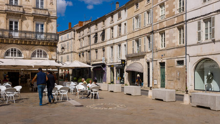 La Rochelle, France - August 31, 2020: People sit at outdoor cafe tables under umbrellas and walk through a city square bordered by historic stone buildings with shops and residential windows.のeditorial素材