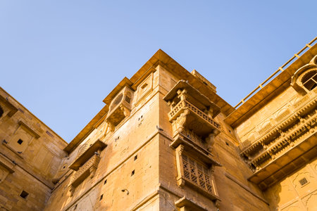 Jaisalmer, India - March 27, 2022: The image shows an upward view of yellow sandstone palace walls with ornate carved balconies and architectural details inside Fort de Jaisalmer under clear daylight.のeditorial素材