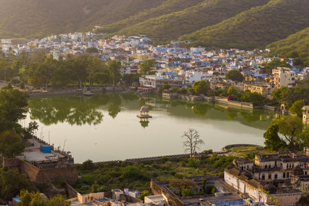 Bundi, India - March 20, 2022: Nawal Sagar Lake is seen with a central pavilion, surrounded by city buildings, trees, and hills in the background under daylight.のeditorial素材