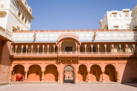 Bikaner, India - March 31, 2022: The main courtyard of Junagarh Fort is shown with red sandstone arches, an ornate balcony, and upper floors featuring white decorative facades under a clear blue sky.のeditorial素材