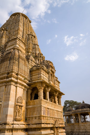 Chittorgarh, India - March 21, 2022: The image shows the intricately carved stone shikhara and upper exterior of Kumbhshyam Temple with a domed pavilion visible in the background under a partly cloudy sky.のeditorial素材