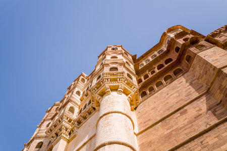 Jodhpur, India - March 25, 2022: The image shows an upward perspective of the massive stone walls and towers of Mehrangarh Fort, highlighting detailed architectural features against a clear blue sky.のeditorial素材
