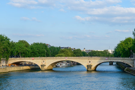 Paris, France - April 27, 2022: The Louis-Philippe Bridge crosses the Seine River with people...