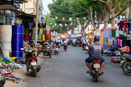 Ben Tre, Vietnam - January 17, 2020: A man wearing a helmet rides a motorbike down a street with...