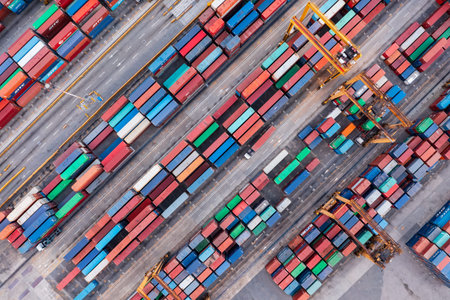 Manila, Philippines - March 23, 2019: Stacks of colorful shipping containers and cargo cranes form geometric patterns in the container yard of the Port of Manila.