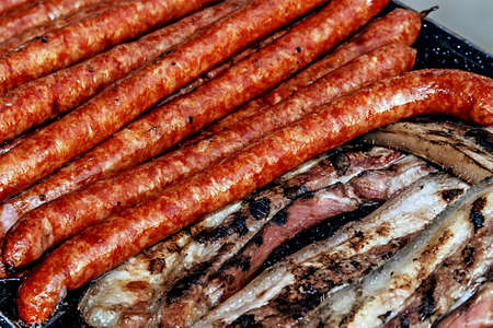 Sausages and ham with fried bacon fried on the grillの写真素材