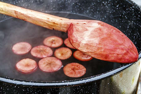 Red wine with apple pieces, boil in a large bowl and mix with a wooden spoon  Romanian tradition for the cold time of the year の写真素材