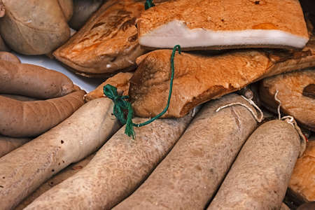 Pieces of bacon and sausages, prepared in house and placed on a tableの写真素材