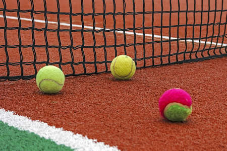 Tennis balls placed around the net on a synthetic field の写真素材