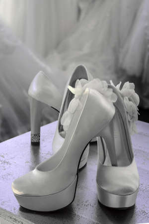 Bridal shoes with silk and decorated with flowers and crystals. Wedding dress on background.の写真素材
