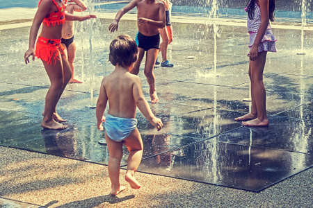 Childhood. Children and youth playing with water in a park. Vintage look.の写真素材