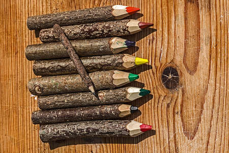 Colored pencils made from branches of trees and placed on a wooden table.の写真素材