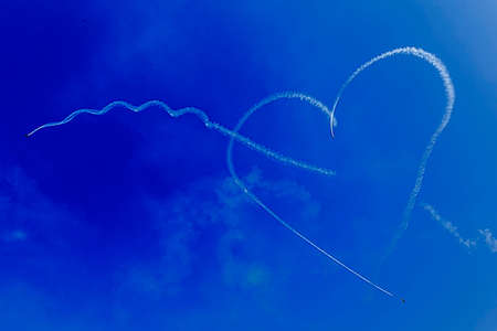 Drawings of smoke in the sky, heart shaped, made from airplanes at a airshow demonstration.の写真素材