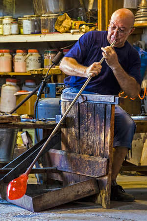 MURANO, ITALY - AUGUST, 5: Glassworker in action in the Murano glass factory on August 5, 2015.のeditorial素材