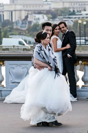 PARIS, FRANCE - OCTOBER 10, 2015: Street photography. Two couples of newlyweds, coming from two continents, which intersect on Alexander bridge in Paris.のeditorial素材