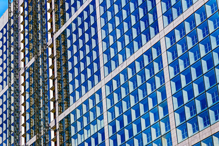 The facade of a modern office building under construction with scaffoldings on the outside.